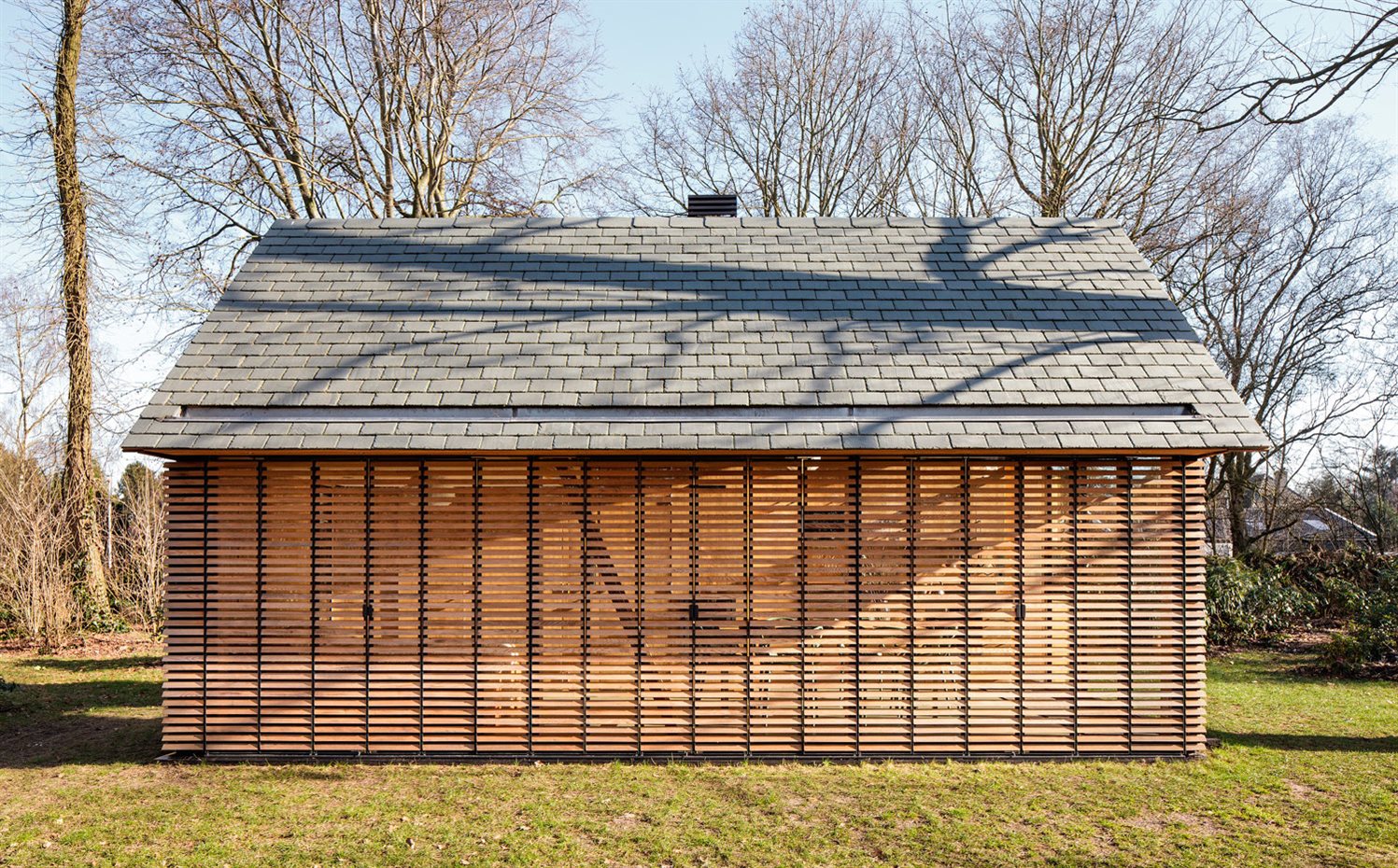 SP2015-Zecc-Tuinhuis-3-HiRes. Las persianas de una de las paredes laterales, la que recibe la luz del sol, se pueden cerrar completamente, recordando al cascarón que era originalmente la caseta