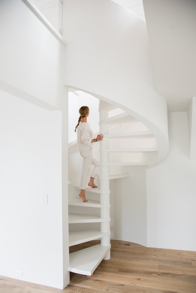 Escalera de caracol de color blanco con mujer subiendo