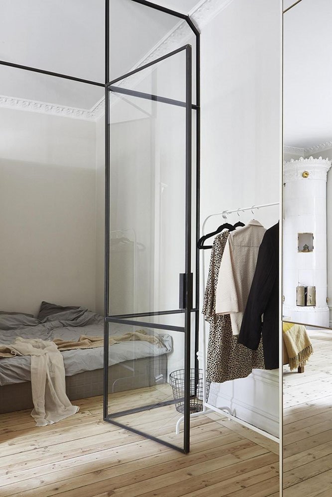 Dormitorio con vestidor separados por una pared de cristal.