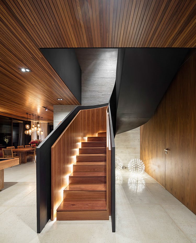 Escaleras de madera con iluminación interior, techo revestido de láminas de madera y luminaria tipo foco y de suelo