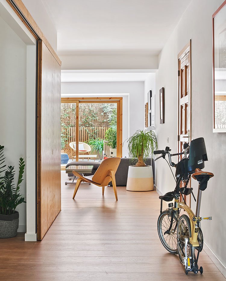 Zona de paso a salo´n y terraza con puerta corredera, bici plegable y butaca de madera