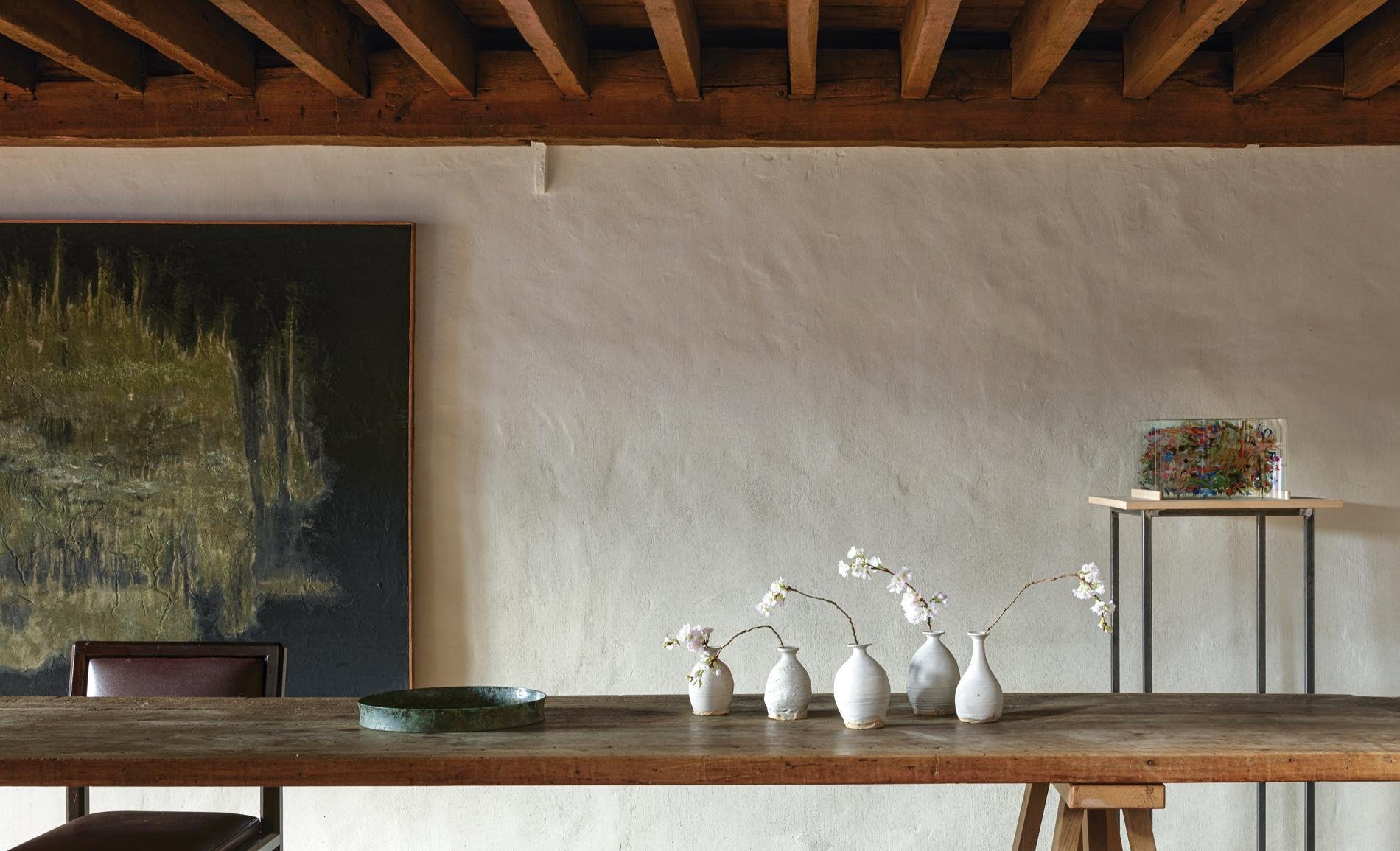 Espacio del diseñador Axel Vervoord con a¡paredes blancas y rugosas y vigas de madera