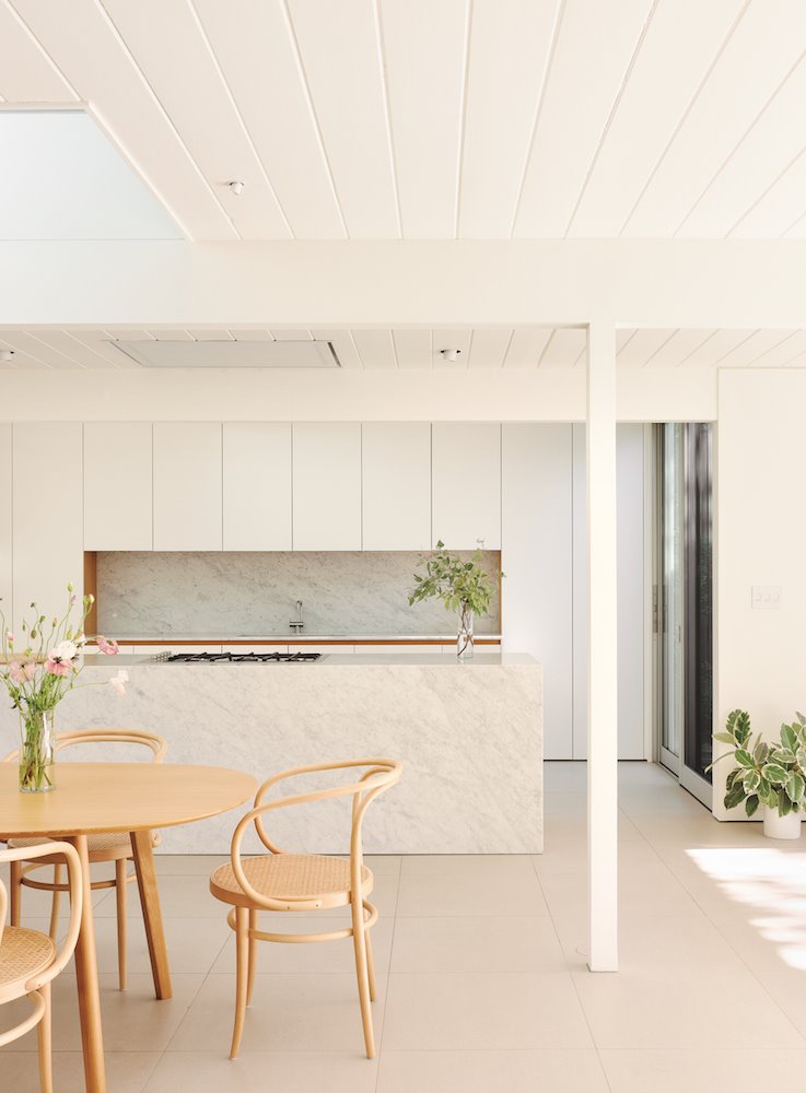 Cocina de marmol blanco con silla de madera