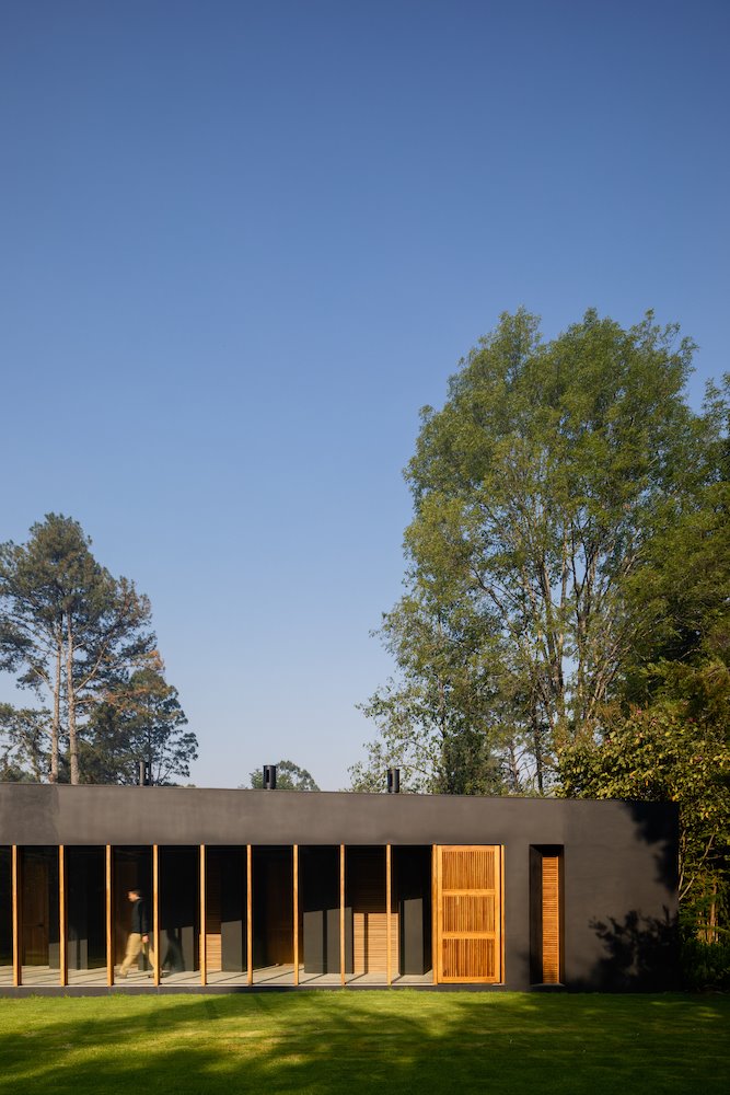 Casa en mitad del bosque con paneles de madera que se abren hacia el exterior