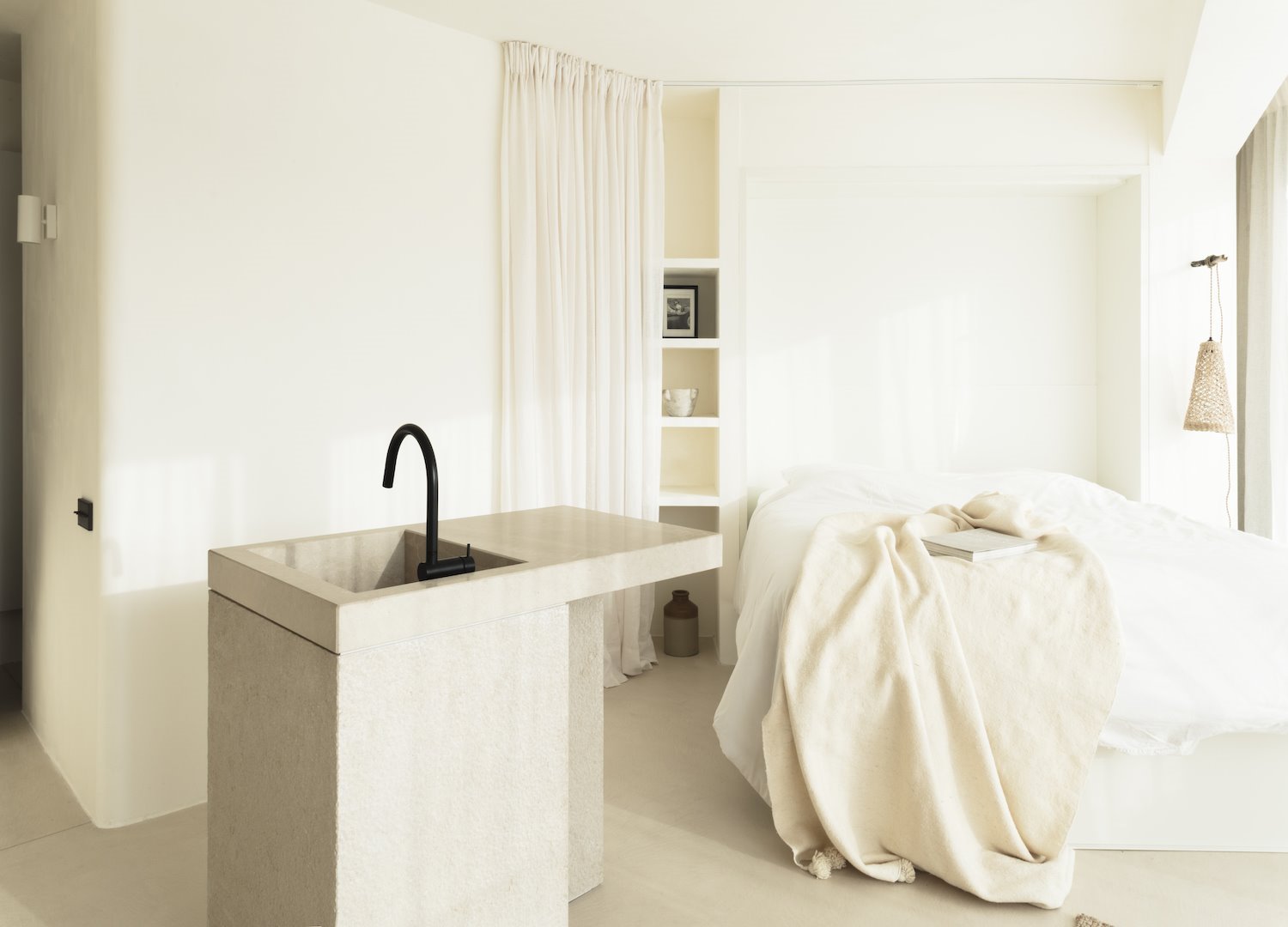piso blanco con cama blanca con una cocina junto al dormitorio