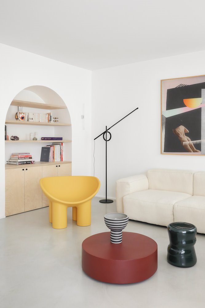 salón con sofá blanco, butaca amarilla y mesa de centro roja circular