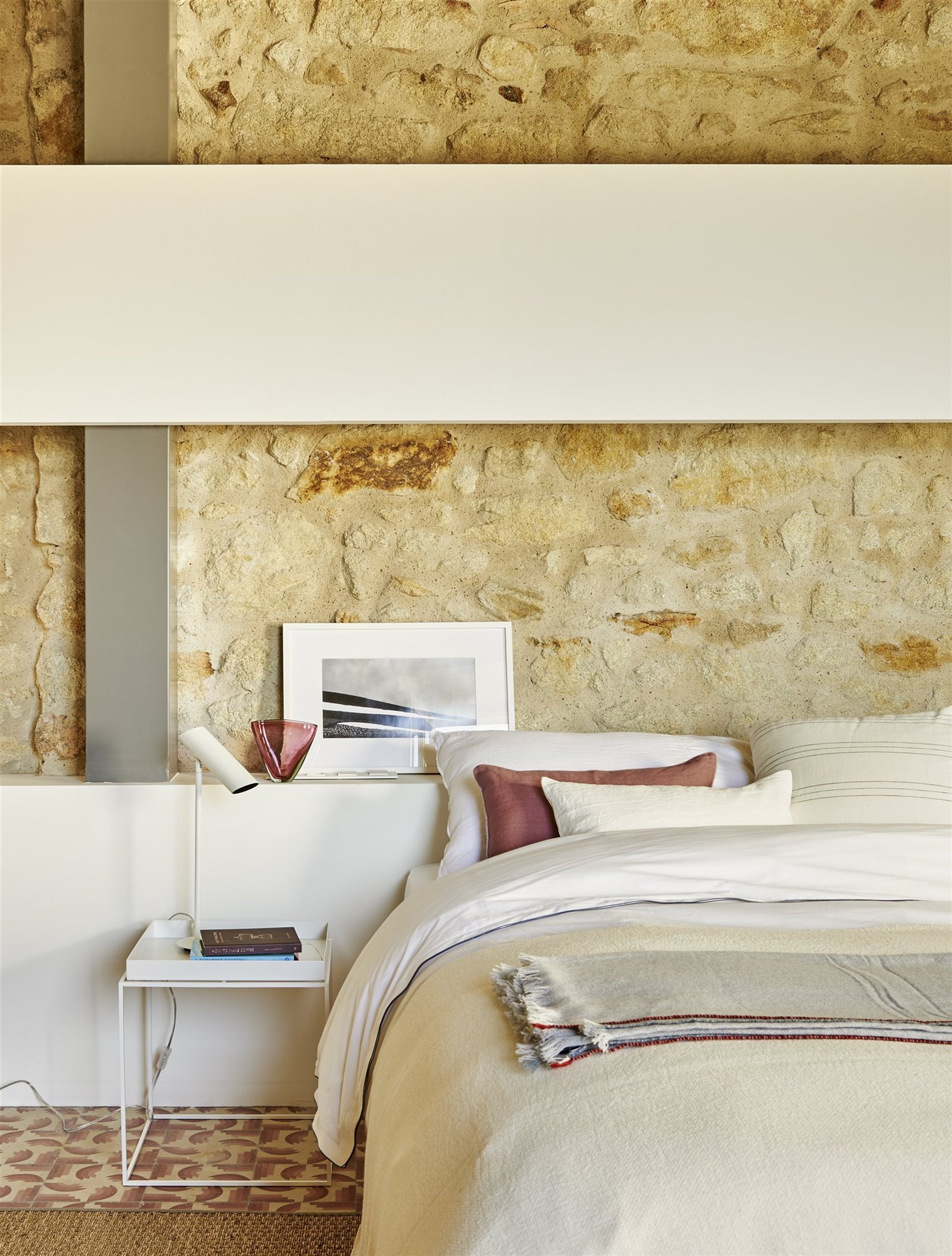 Dormitorio con pared de piedra y cuadros en el cabecero
