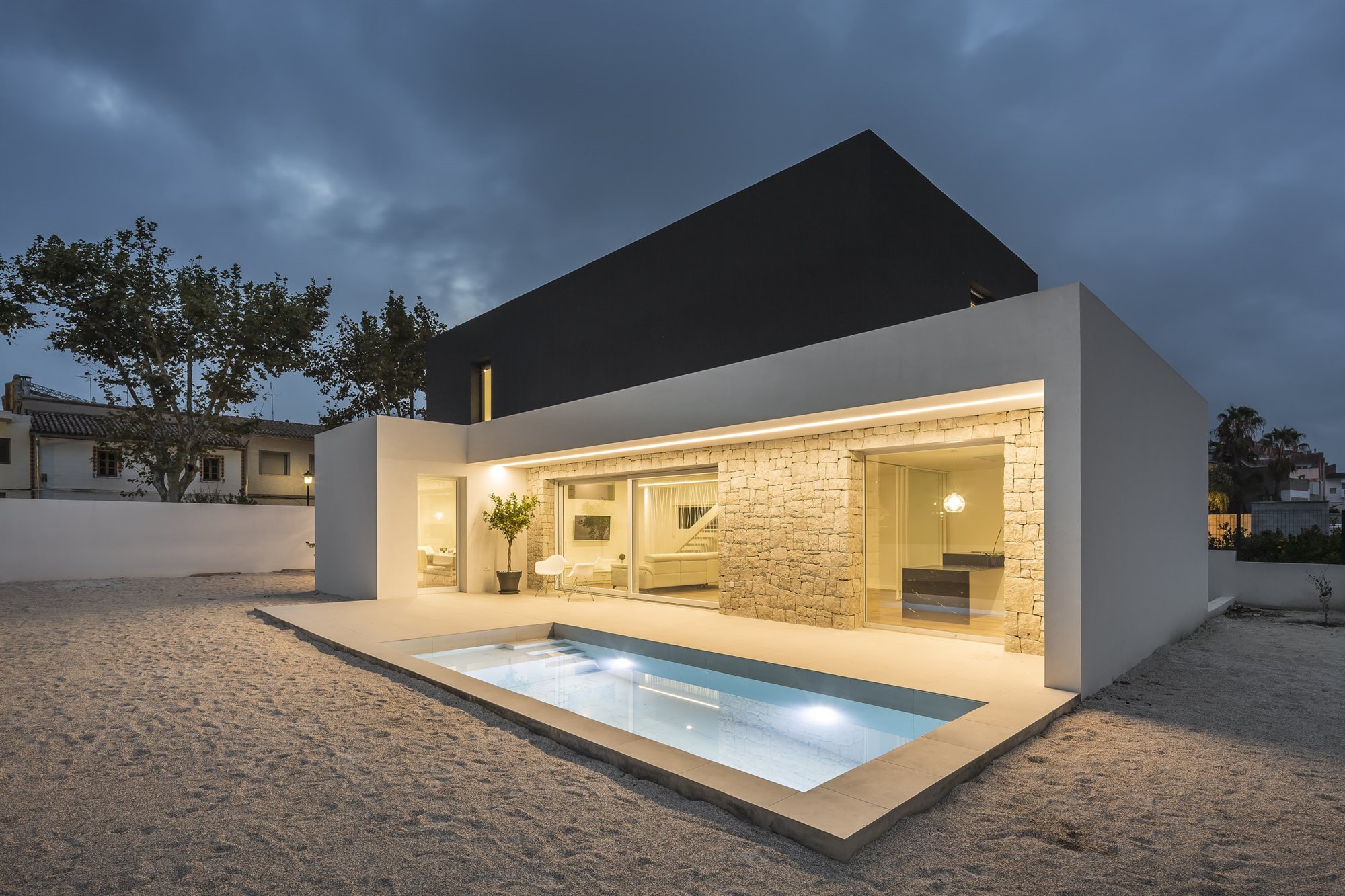 Casa moderna con fachada en blanco y negro en Valencia vista de noche con piscina