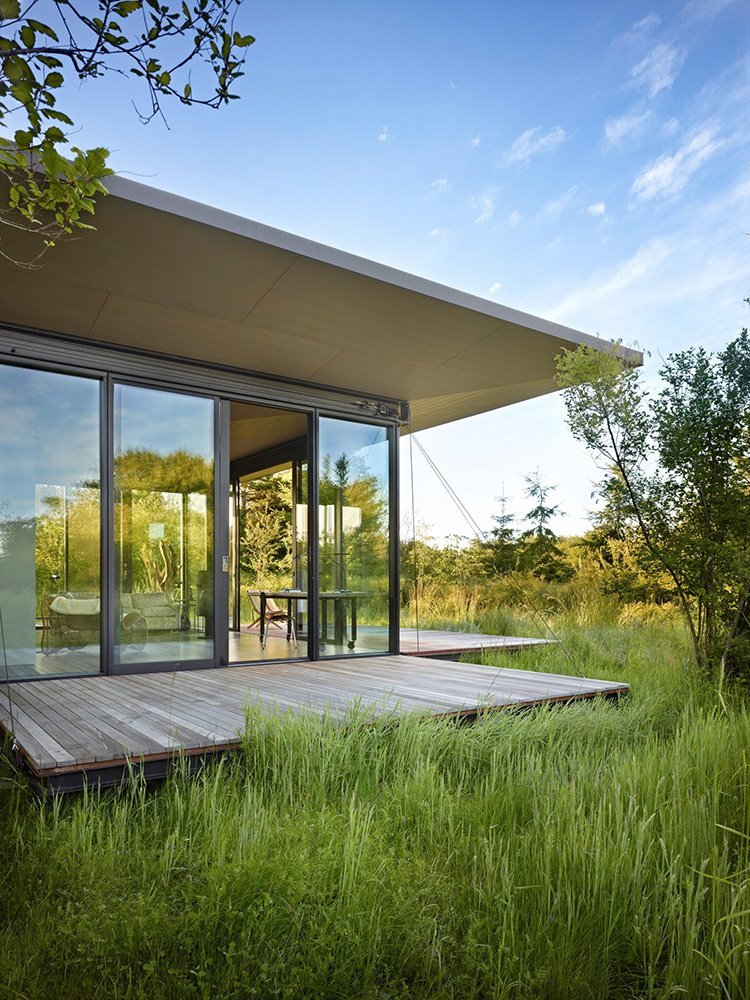 Casa moderna en la naturaleza de madera y cristal con plataformas desplegables
