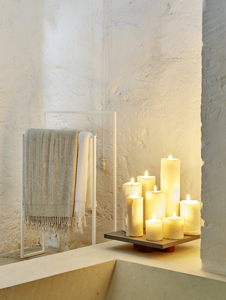 Velas encendidas en un ban~o moderno con paredes encaladas en blanco. Luz con vida