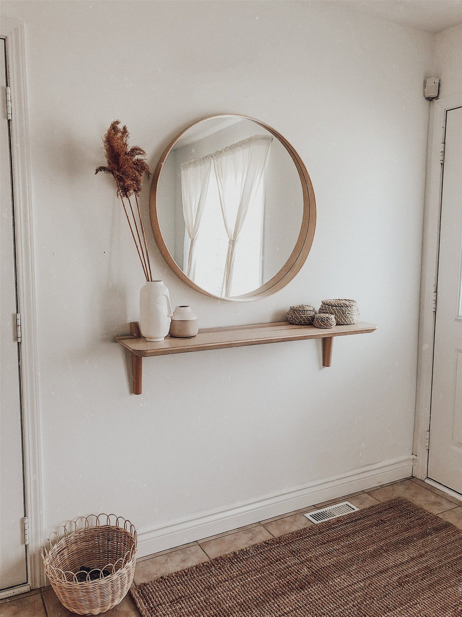Recibidor entrada de casa con estanteria de madera y espejo redondo