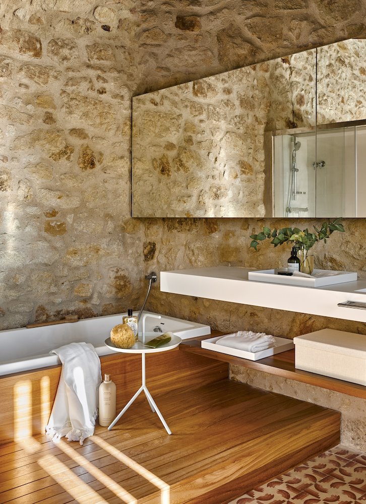 baño de piedra con suelo de madera y bañera