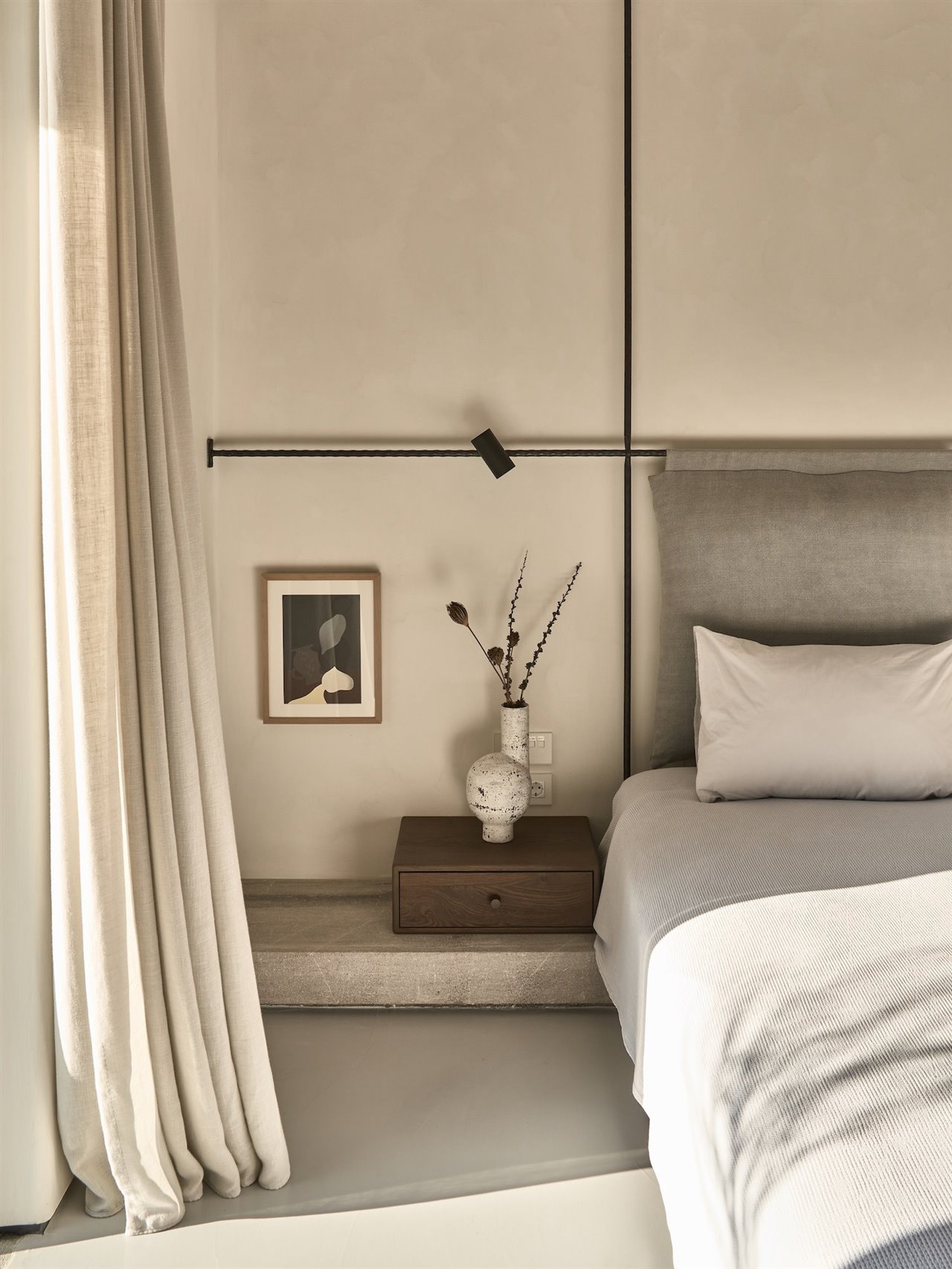 Dormitorio con cabecero de color gris y suelos de cemento pulido