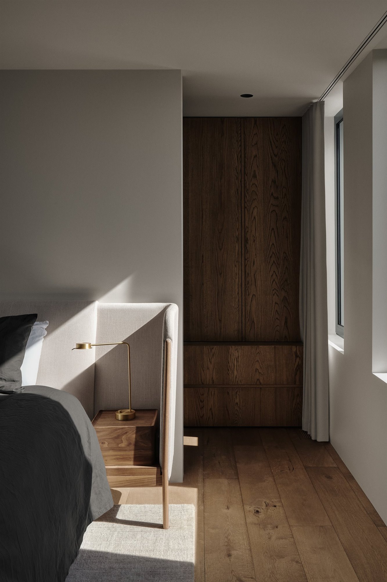 Dormitorio con cabecero tapizado y armario de madera.