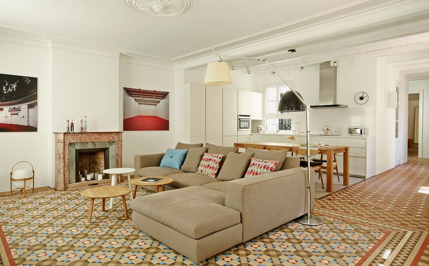 Salón con sofá en forma de L y suelo hidráulico en tonos tierra.