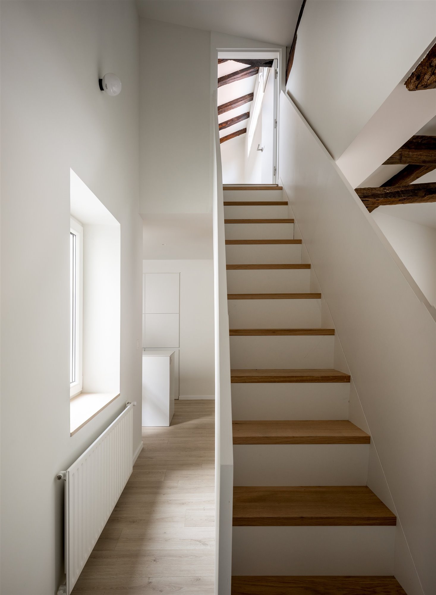 Escaleras con barandillas blancas y escalones de madera.