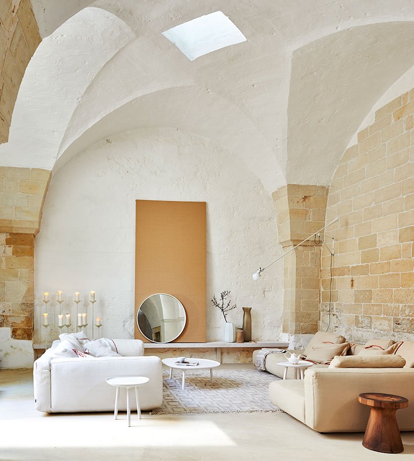 Salón abovedado con paredes de piedra y muebles modernos.