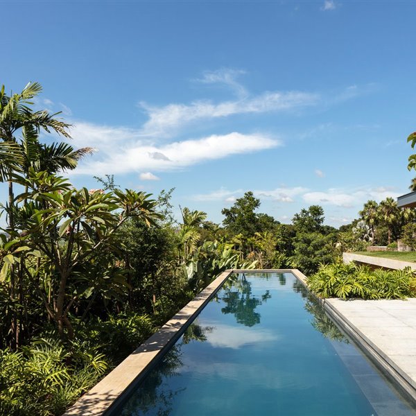 piscina-alargada-exterior-vegetacion-tropical-terraza-exterior-con-butacas-grises 78c13b83 1500x930