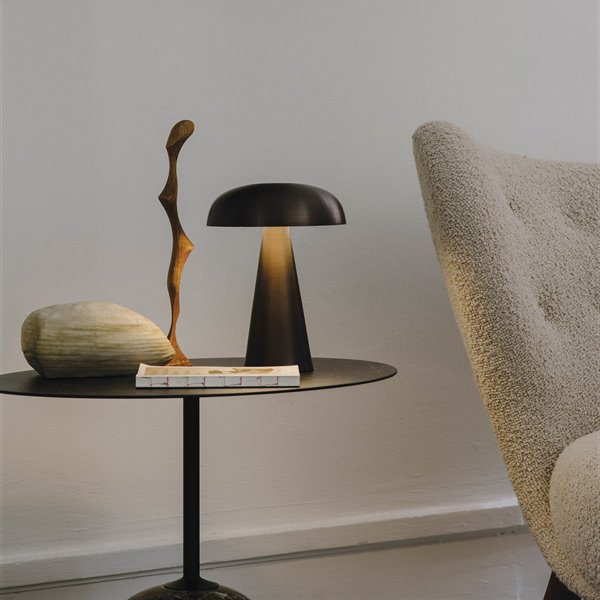 lámpara seta negra en mesa con esculturas y libro