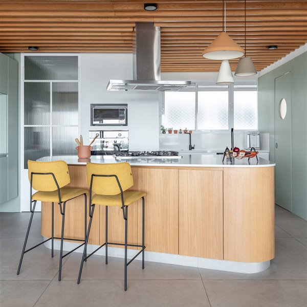 Una gran isla de cocina define la distribución de este apartamento, donde manda la luz natural, el diseño orgánico y el color verde