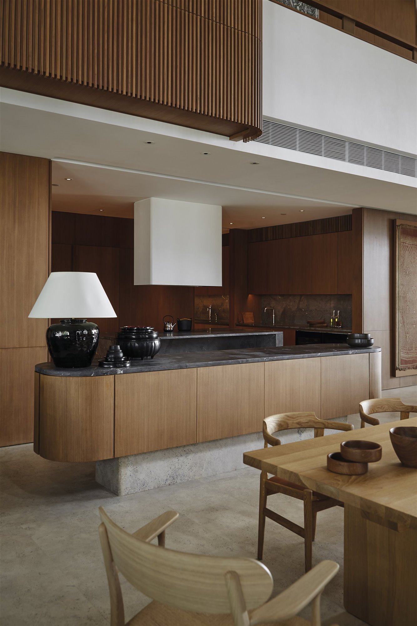 Cocina de una casa moderna con isla de madera, base de márnol y encimera negra. 