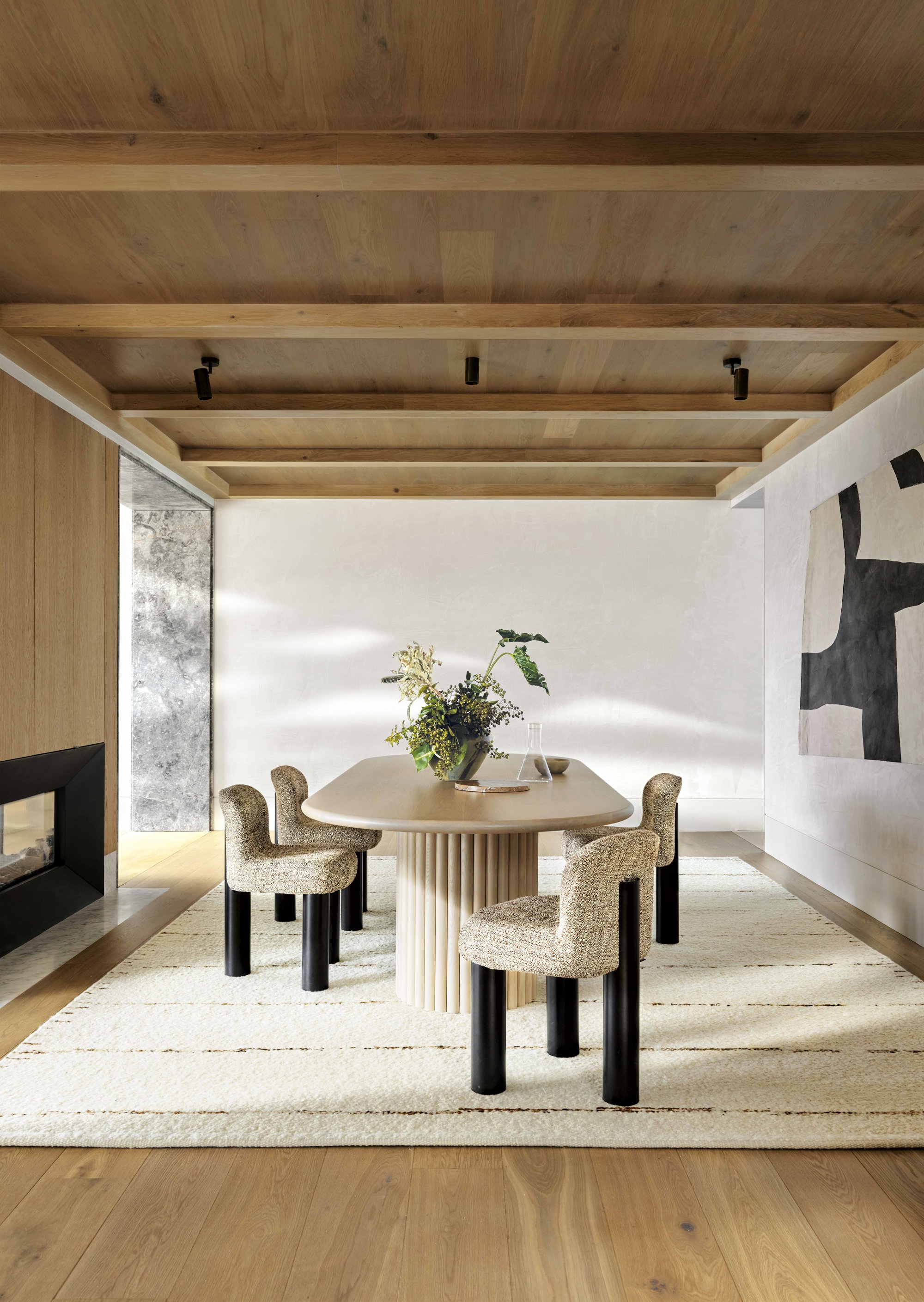 Comedor con sillas tapizadas, alfombra y techo de madera.