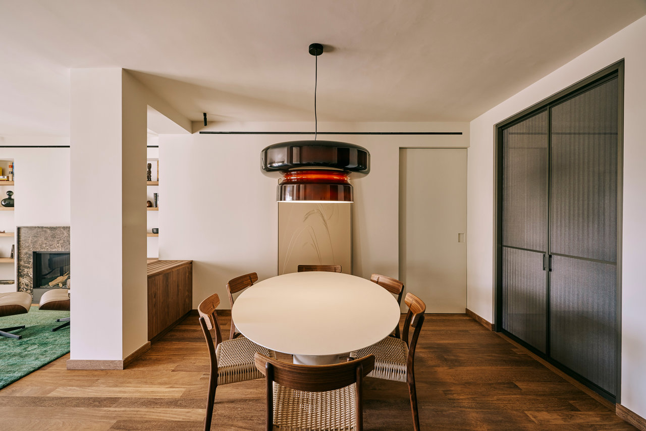 Una lámpara de Marset da carácter al espacio dedicado al comedor. A la derecha, unas puertas translúcidas dan intimidad a la cocina. 