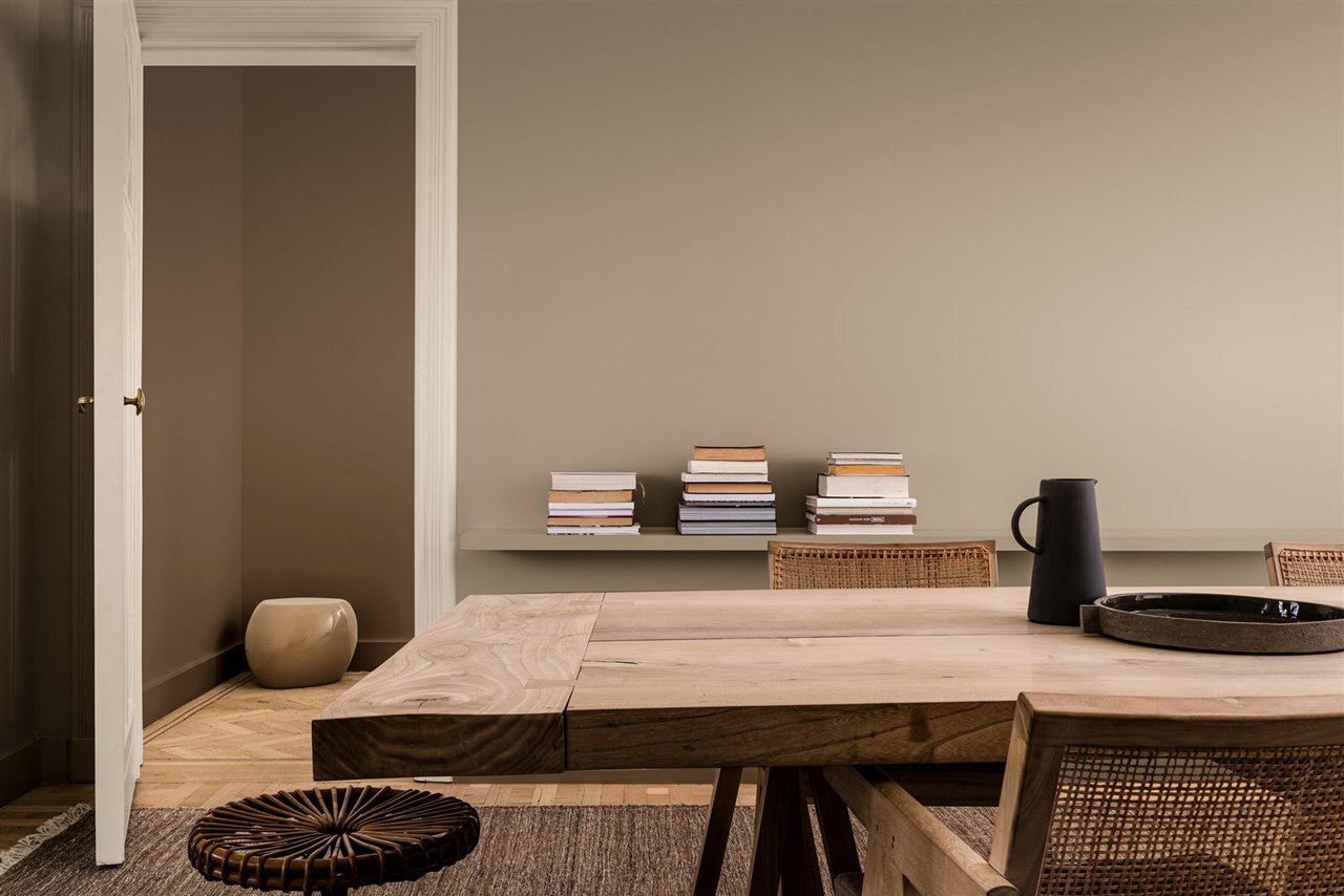 Salon con mesa de madera y libros paredes en color beige