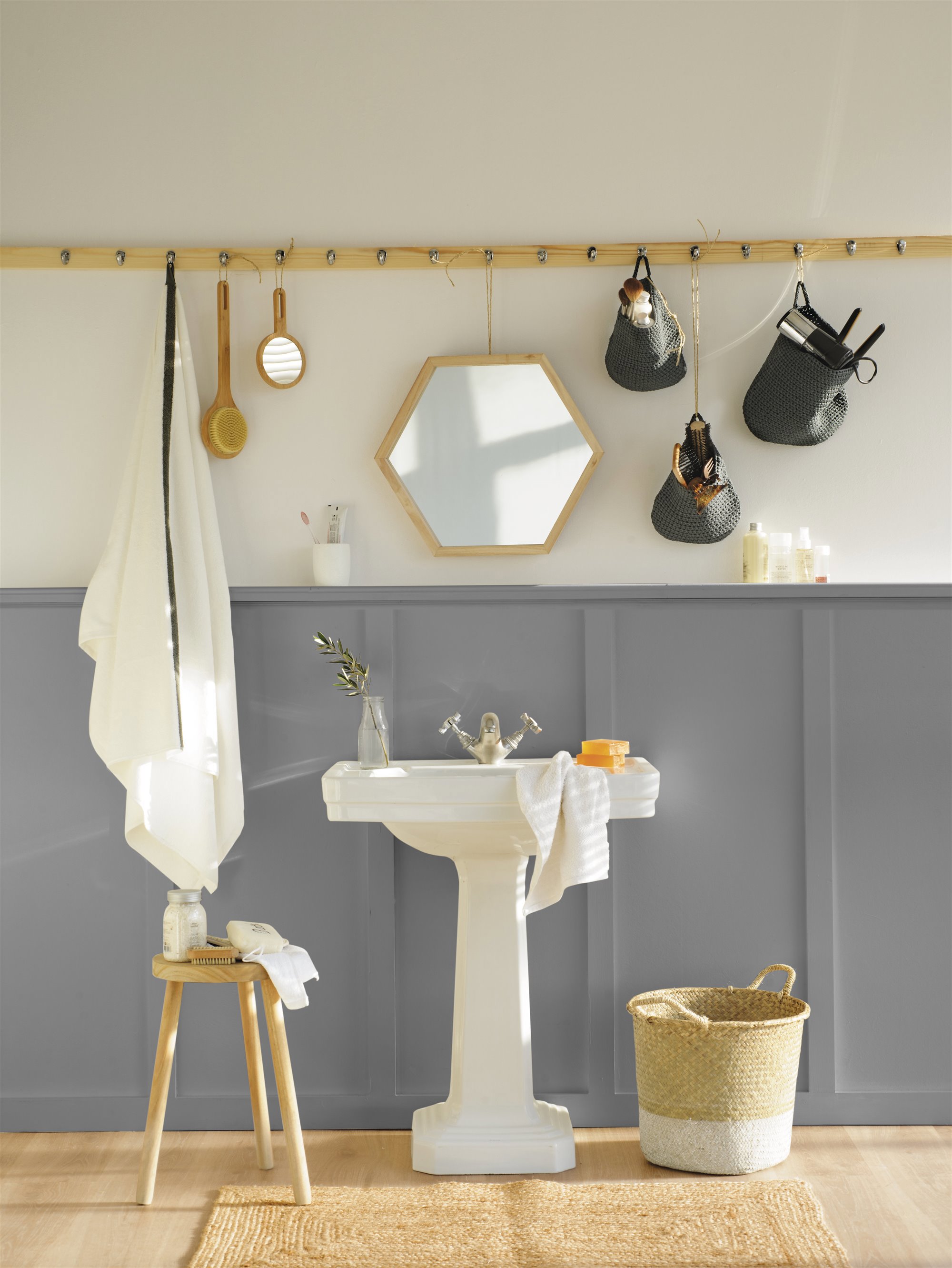 baño con pared azul y blanca y colgador de madera con espejo, cestos, secador, toalla