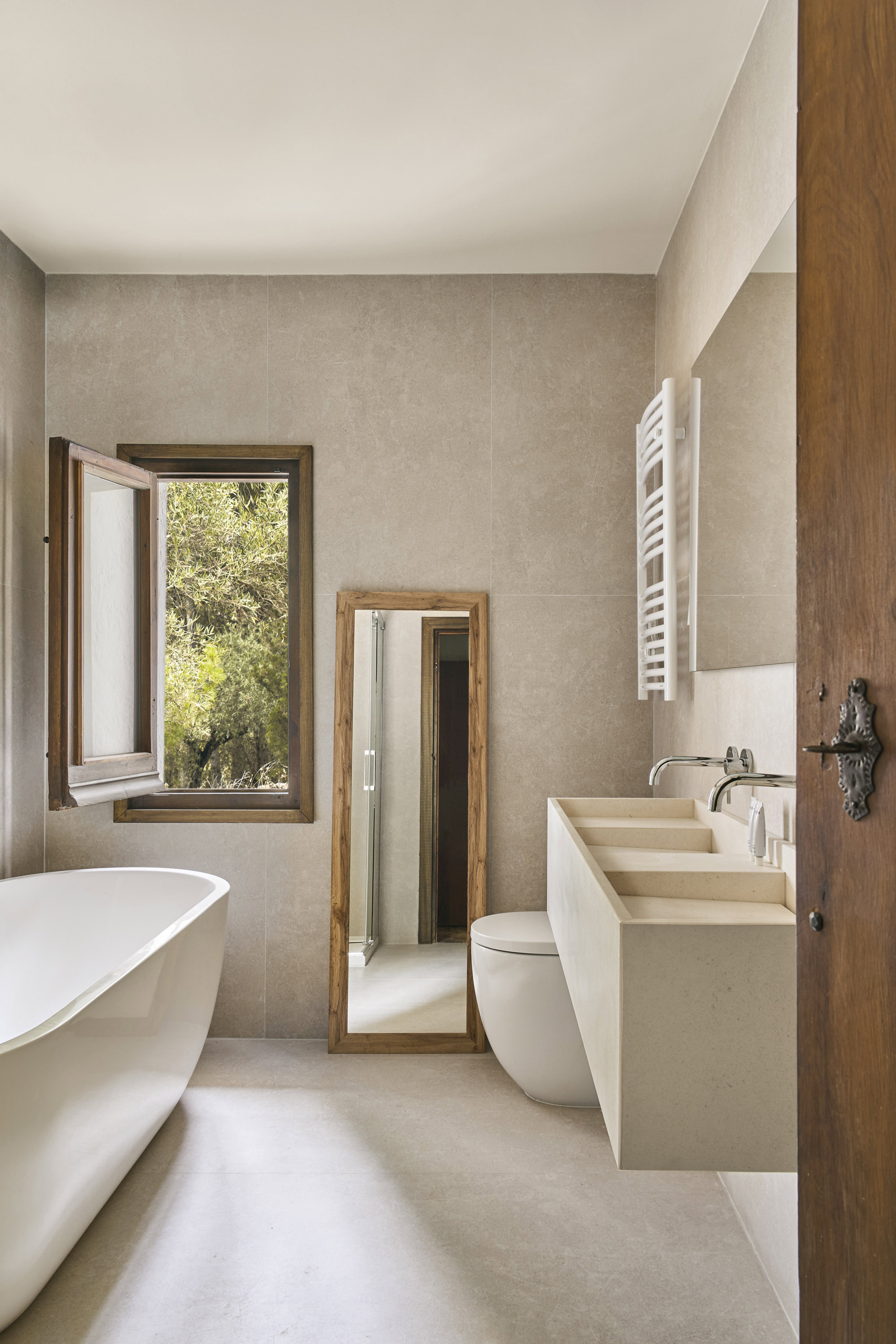  Baño con lavabo de piedra caliza blanca paloma, diseño de Bueno; grifería, de Rovira, y bañera, de Hudson Reed.