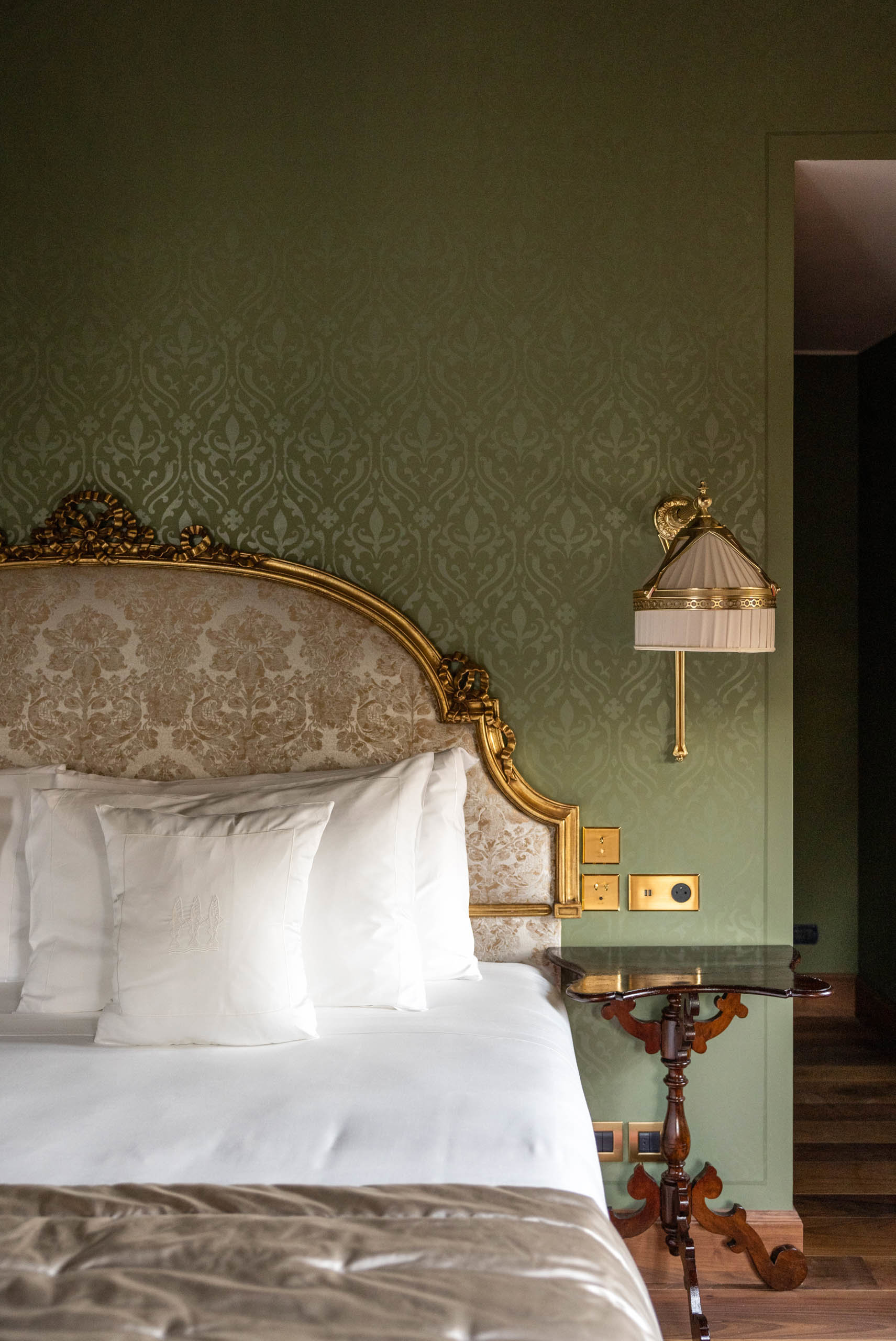 dormitorio clásico con pared verde y cabecero de cama dorado