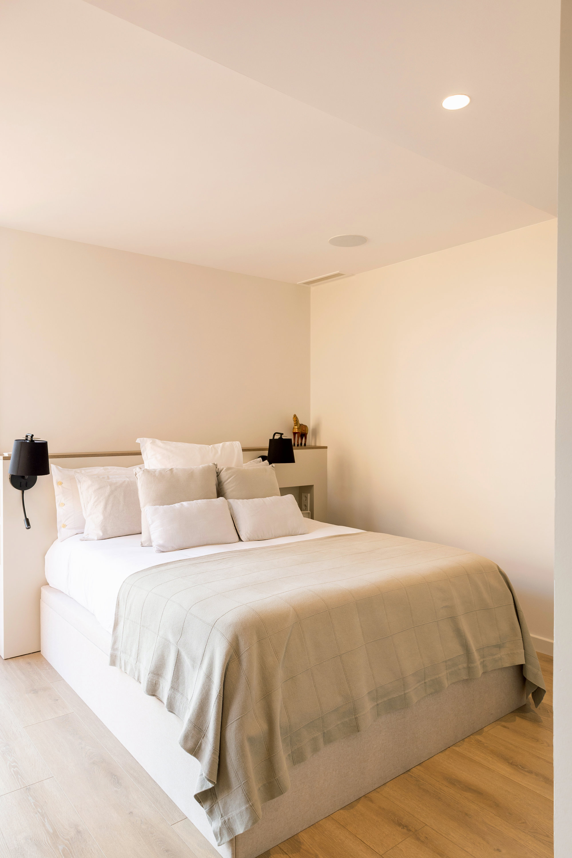 Dormitorio con textiles blancos y mesillas a medida