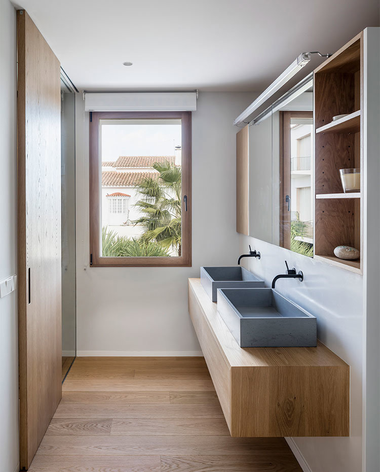 Cuarto de baño con suelo, puerta corredera y mobiliario en madera, pilas en gris