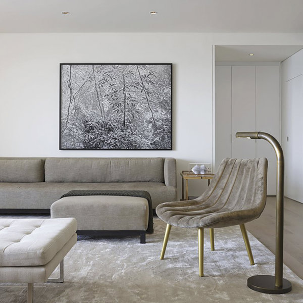 salón gris con sofá butaca cuadro y lámpara de pie dorada de arthut casas