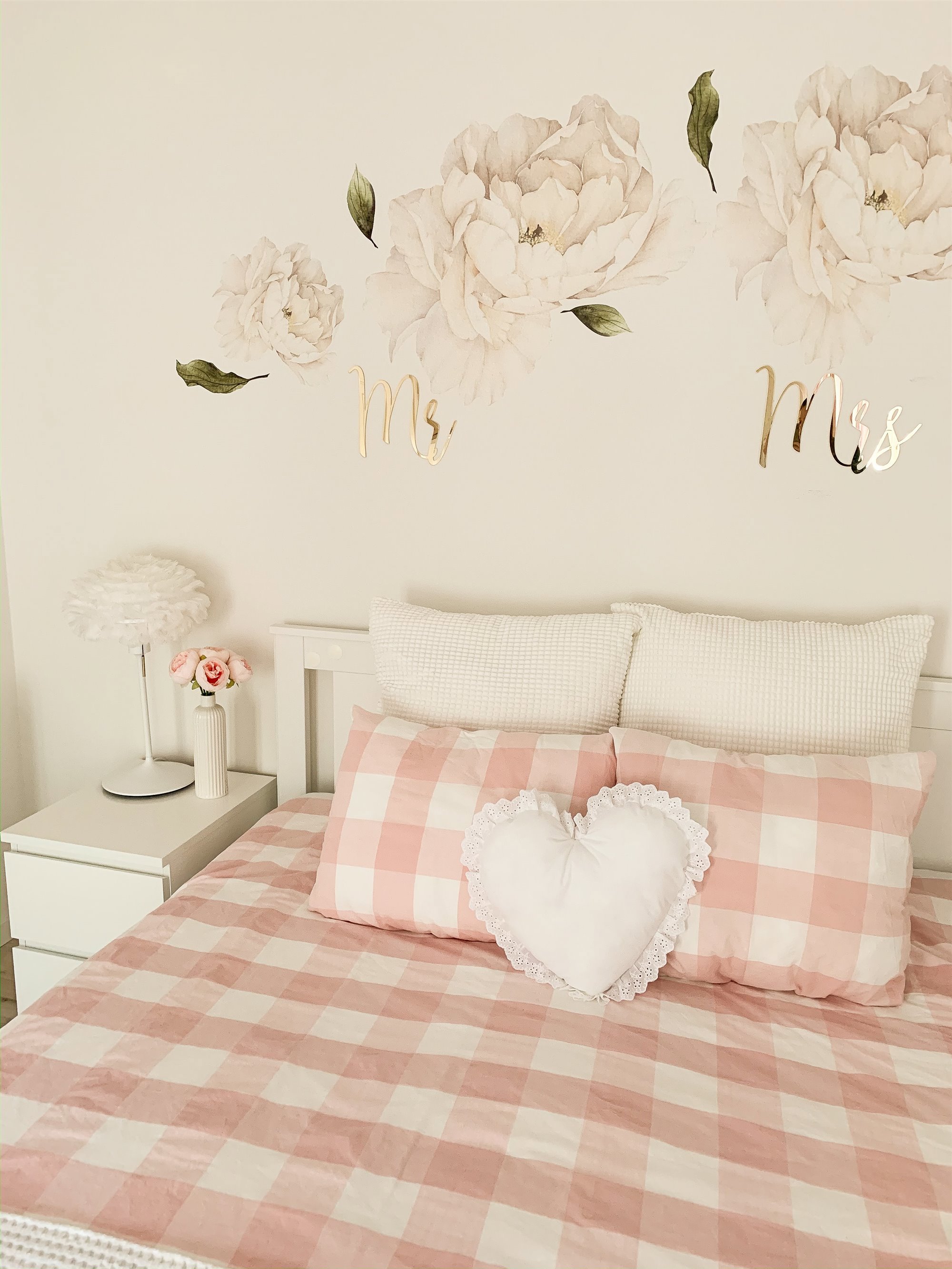 cama con colcha a cuadros rosas y blancos y un sofa con forma de corazon