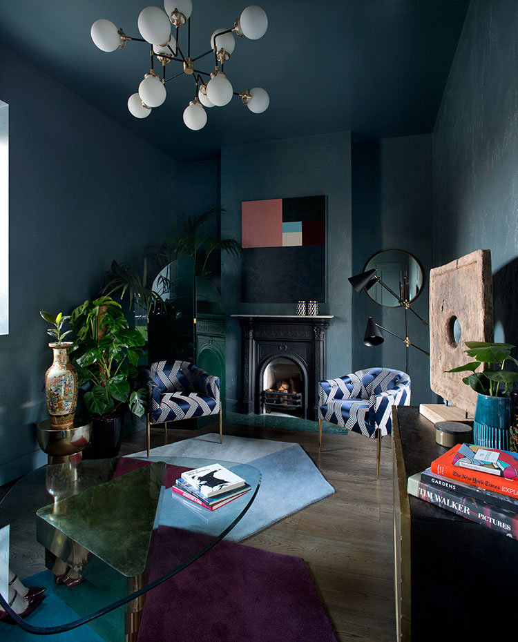 Salón con paredes y techos pintado en tonos azules, butacas en terciopelo azul, mesa de centro con sobre de cristal y chimenea.
