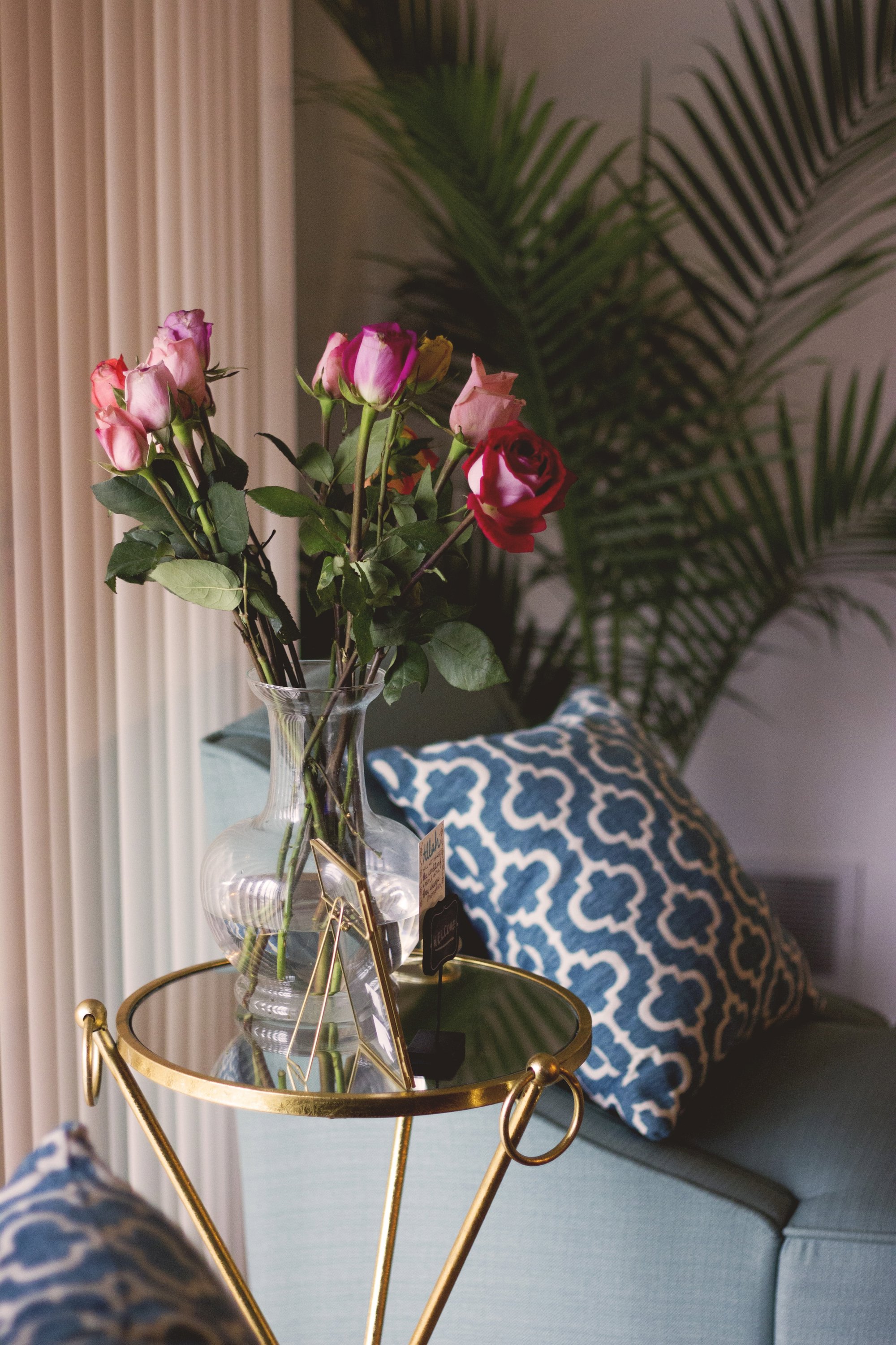 mesa auxiliar con superficie de espejo y un jarron con rosas