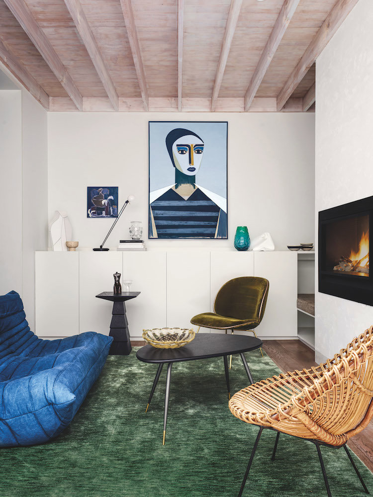 Salon con chimenea, sofa azul y moqueta de color verde