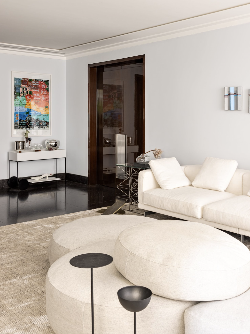 salon con sofas blancos, alfombra y un cuadro de colores