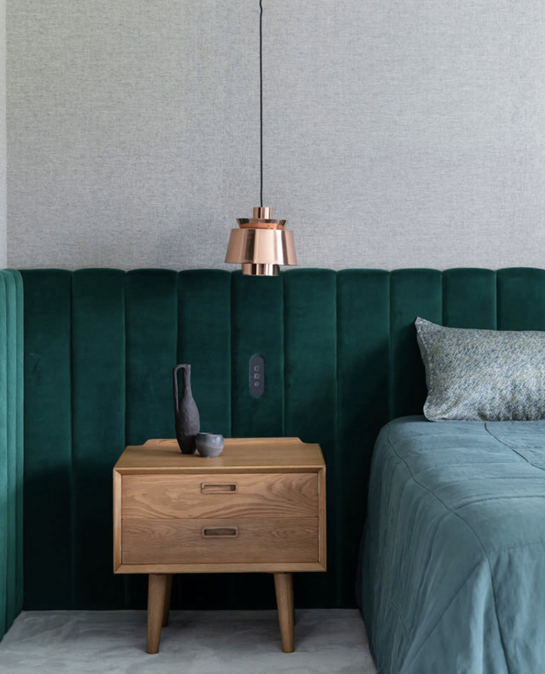 dormitorio en verde y gris con mesilla de madera y lampara colgante dorada