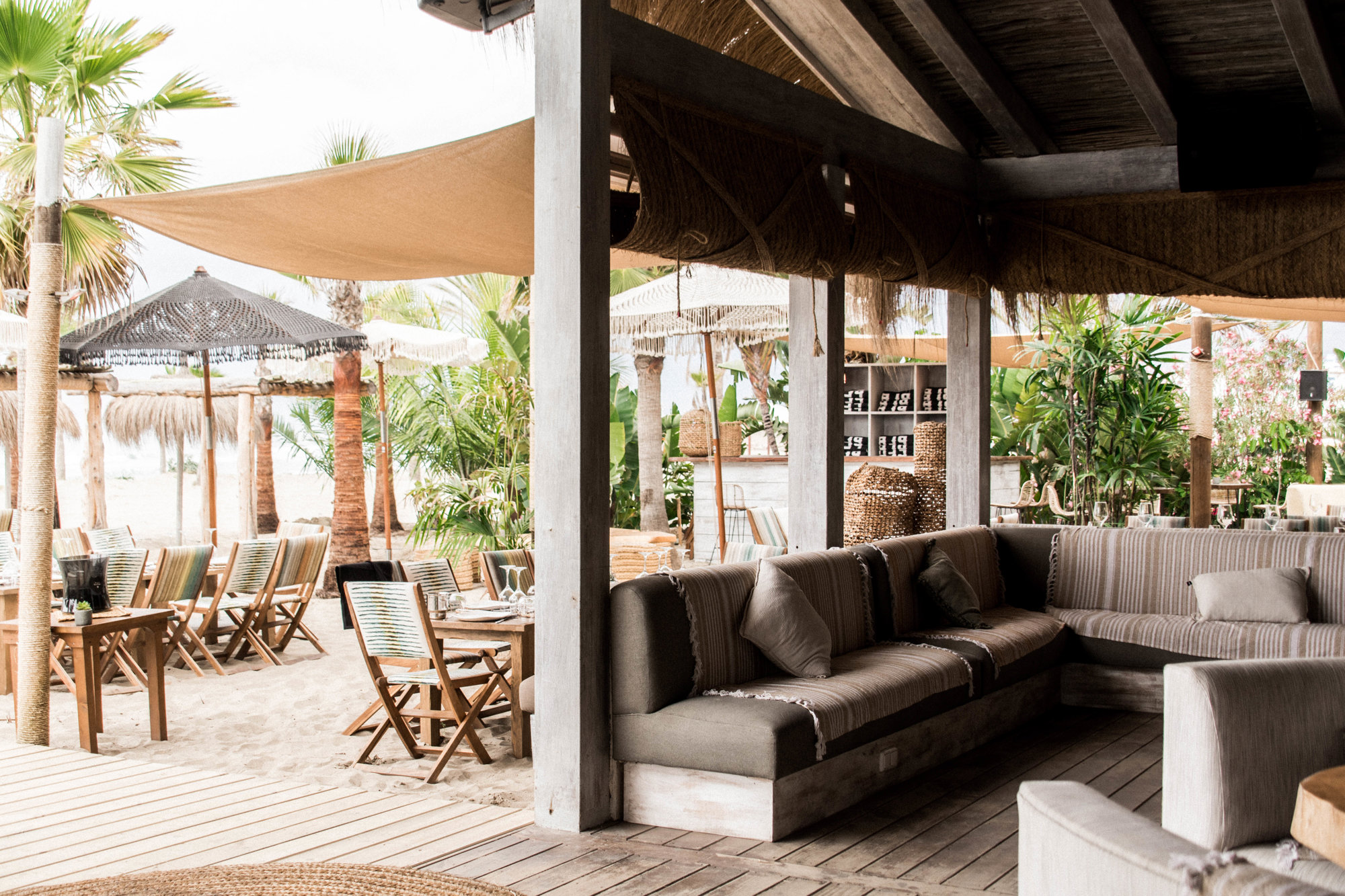 local Playa Padre con decoracion boho chic, sofas grises y parte de la terraza con palemeras