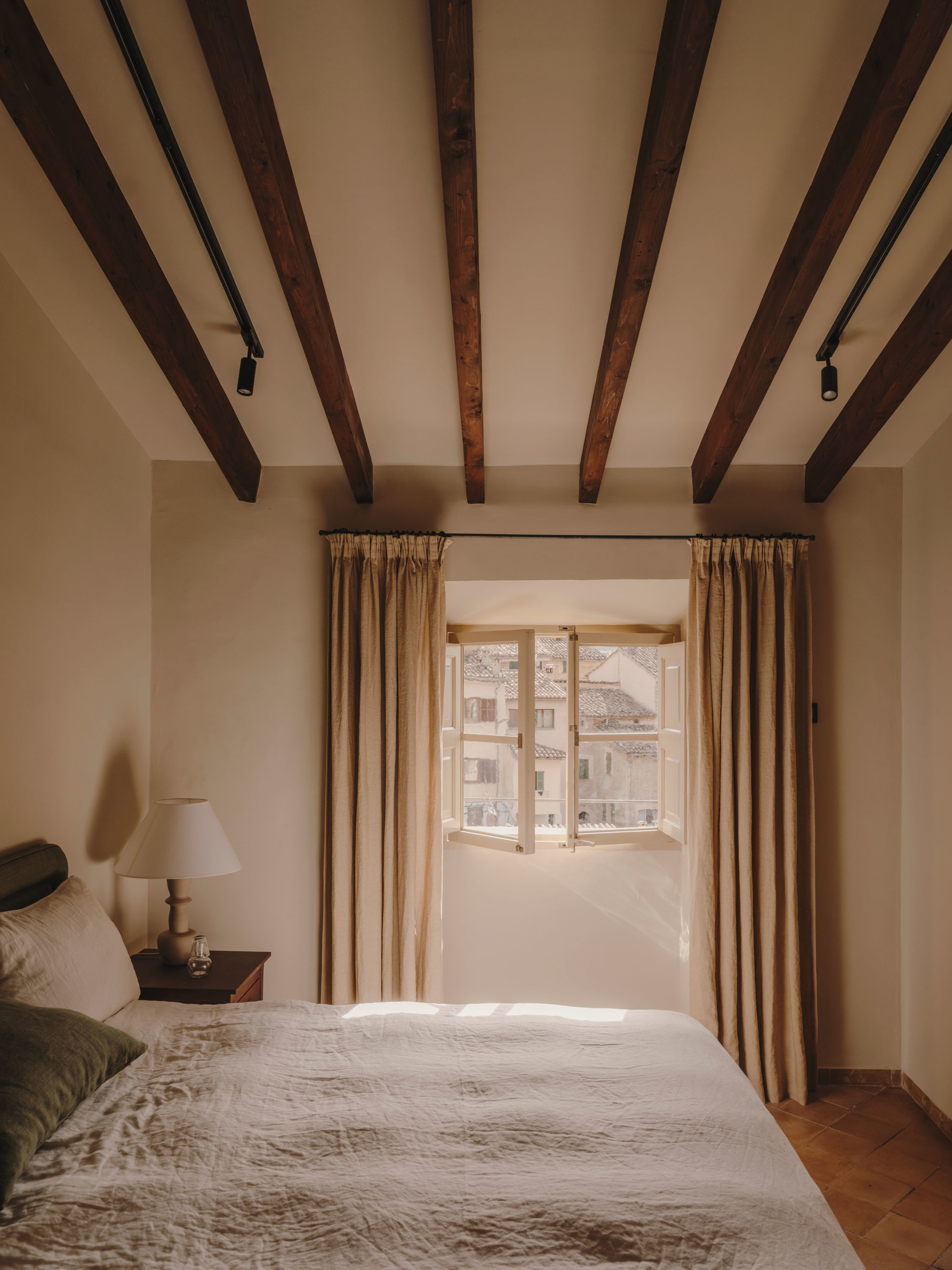 Dormitorio con vigas a la vista y ventana de madera