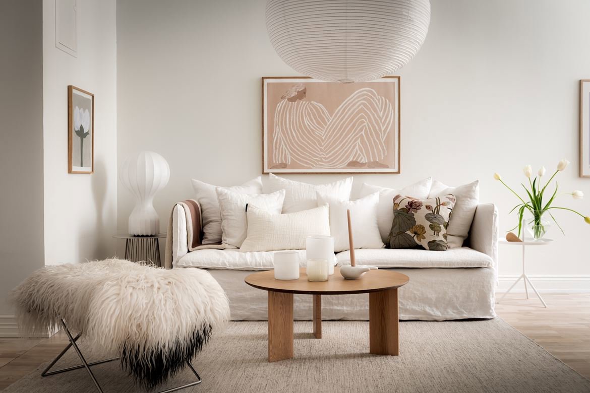 Salón pequeño con sofá blanco, mesa de centro redonda y manta de pelo largo.