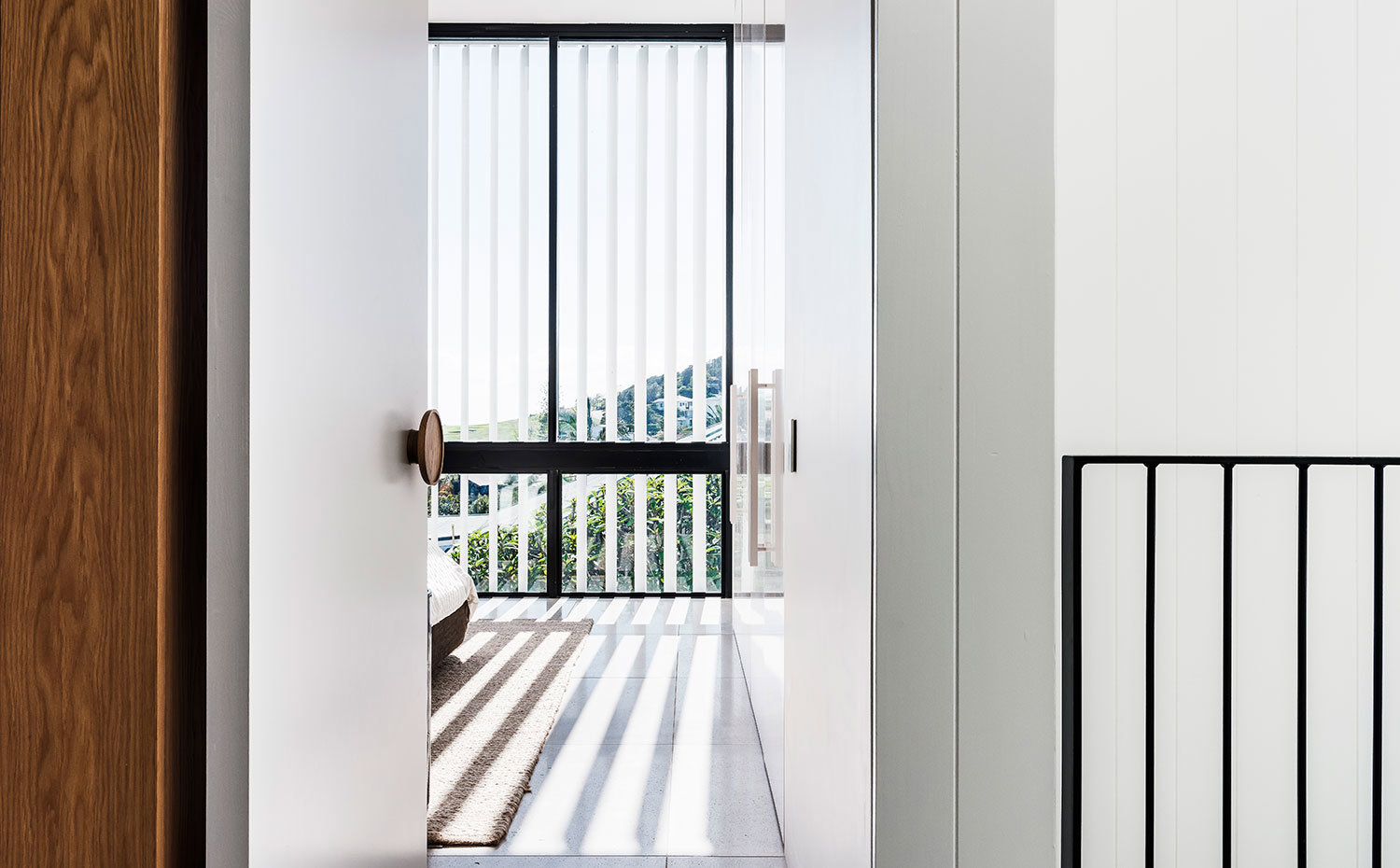 Puerta de acceso a dormitorio con tirador en contraste con puerta en blanco, estor vertical para controlar la entrada de luz