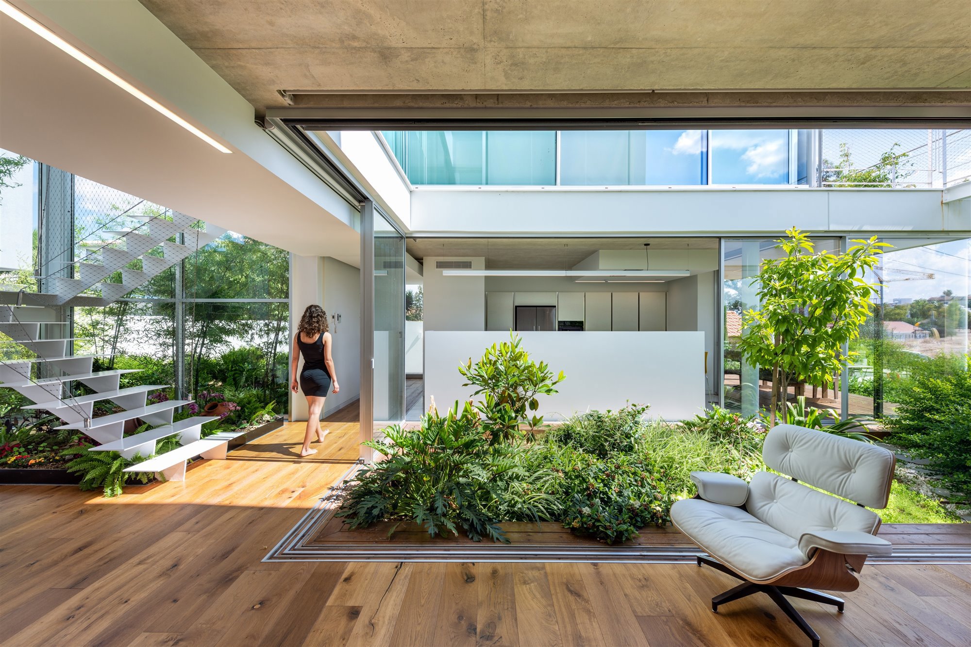 Casa moderna con patio interior con plantas y una butaca color gris claro.