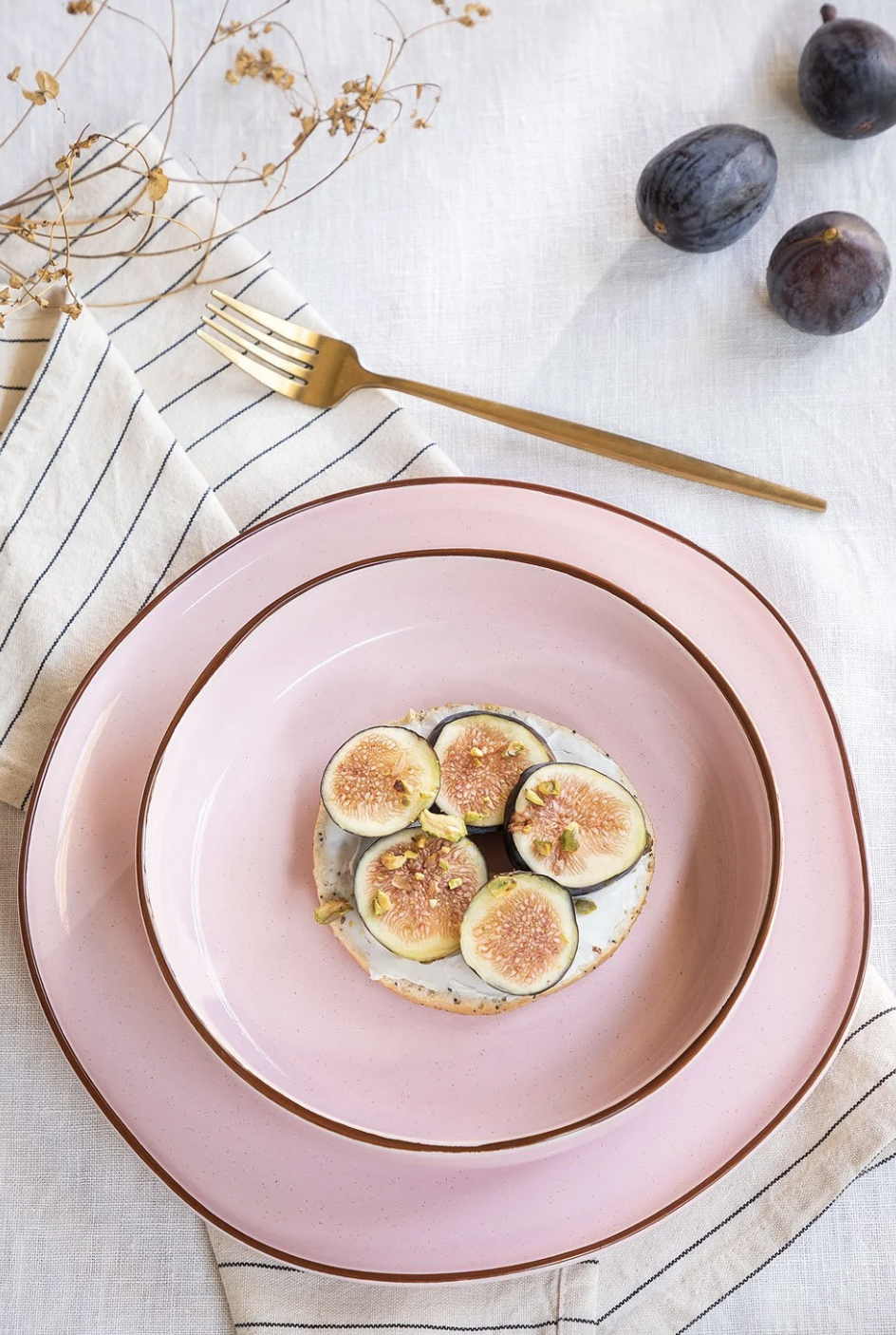 juego de platos de color rosa con tenedor dorado y fruta de adorno