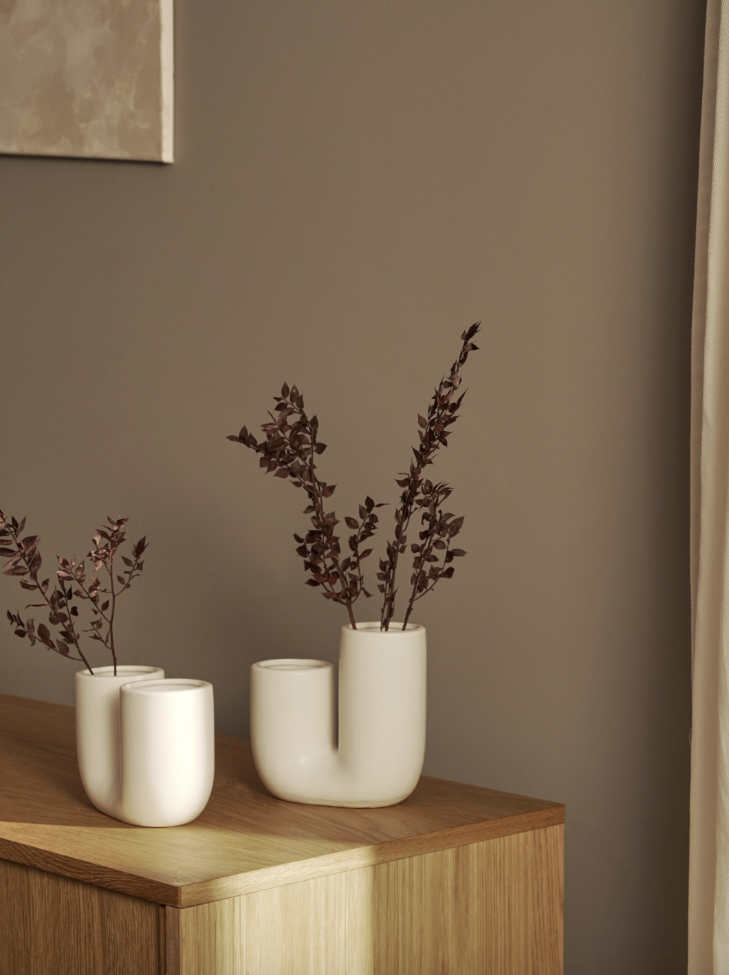 jarrones con forma tubular en blanco con plantas sobre mueble de madera