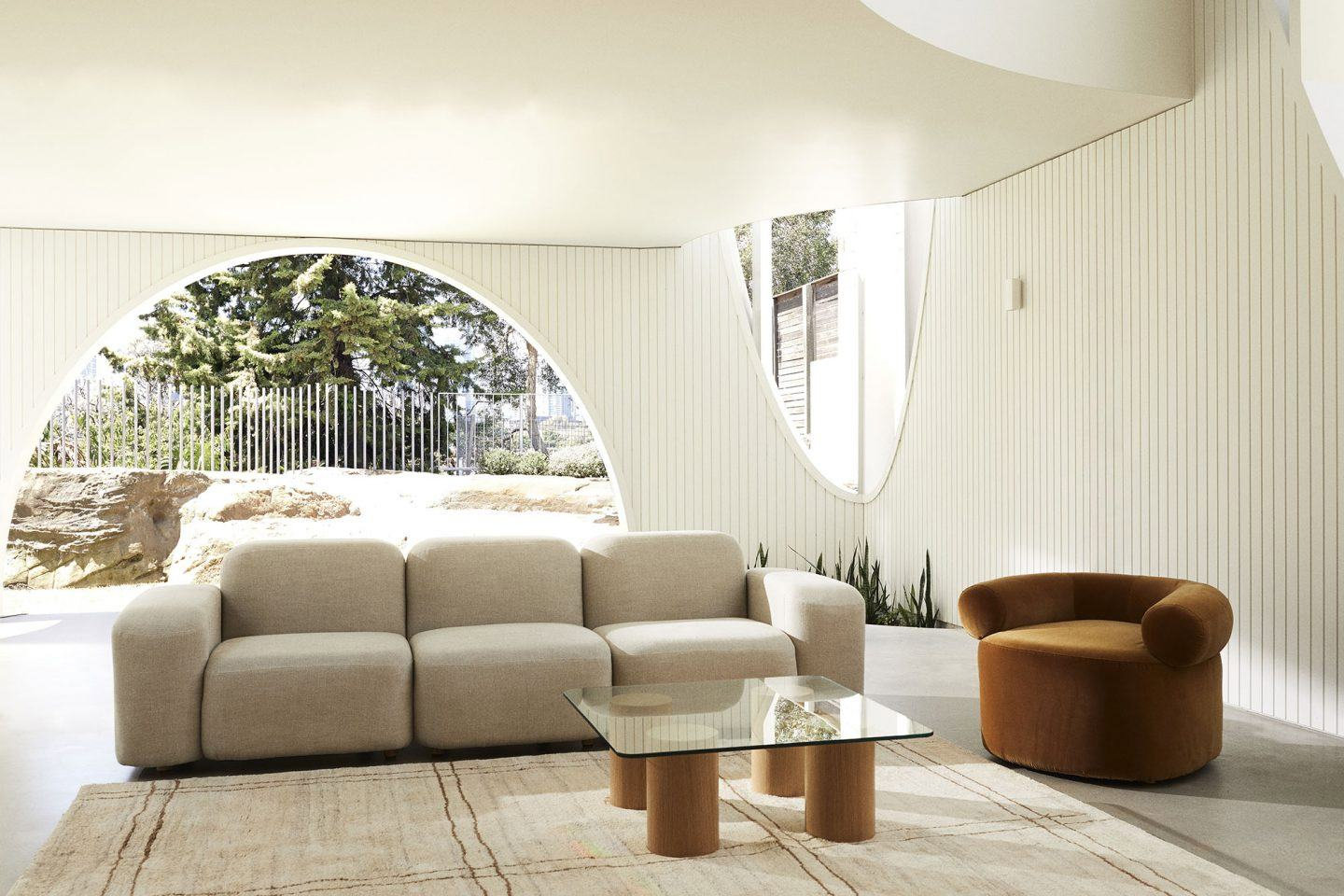 Salón con sofá de tres piezas color blanco arena y sofá individual color marrón