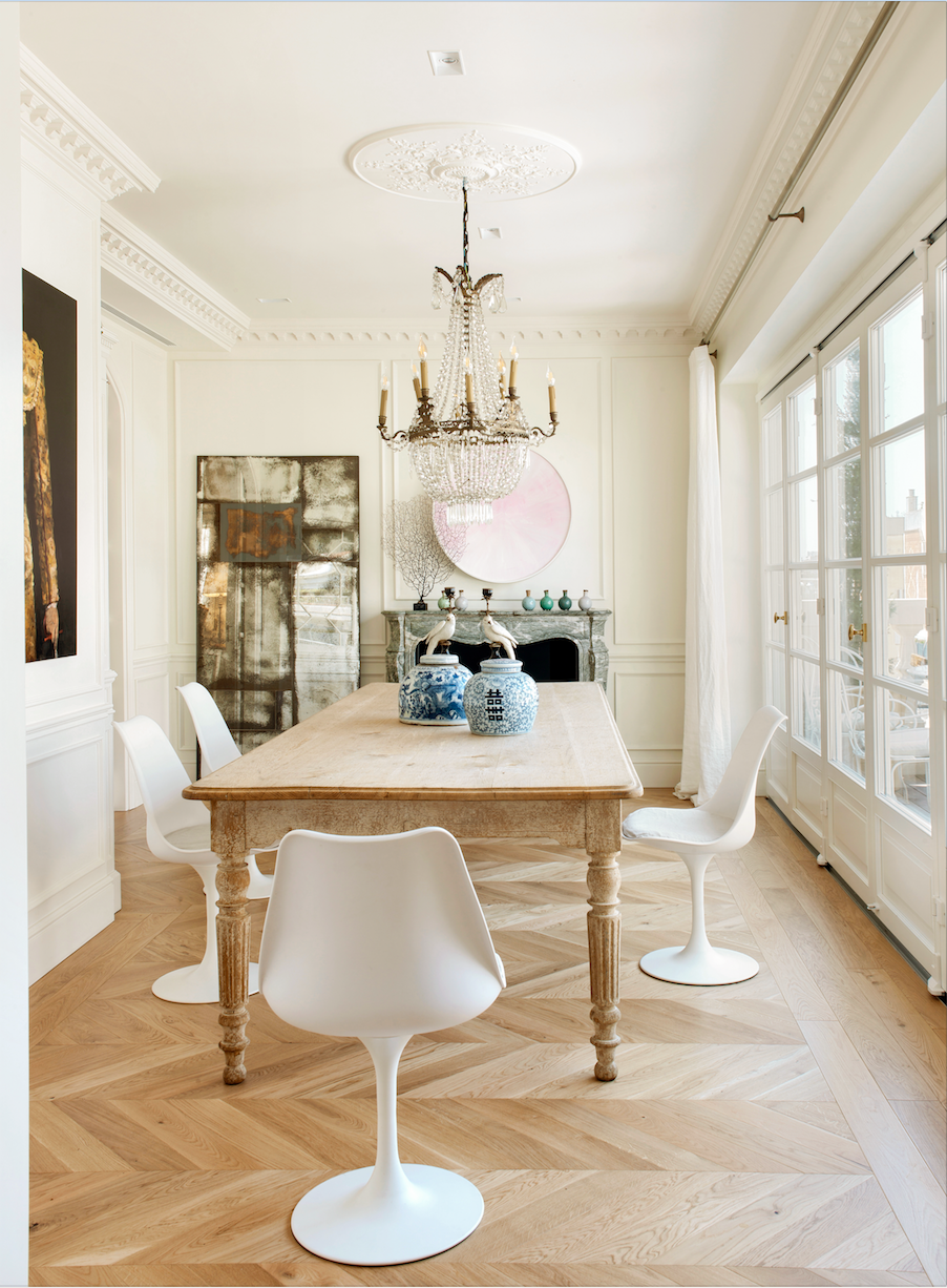Comedor con mesa de madera, sillas Tulip blancas y lámpara de araña