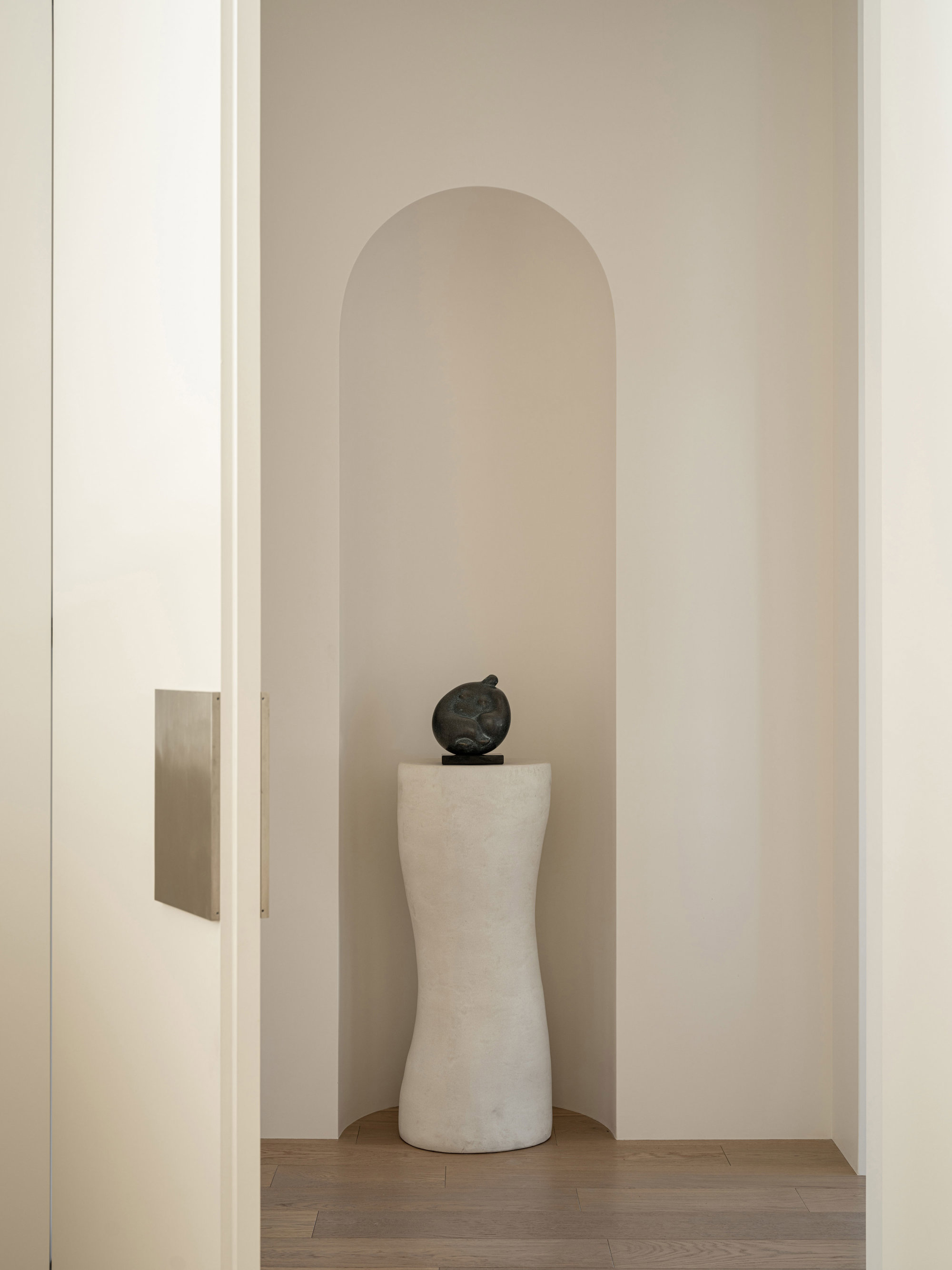 puerta blanca con una escultura sobre pedestal blanco